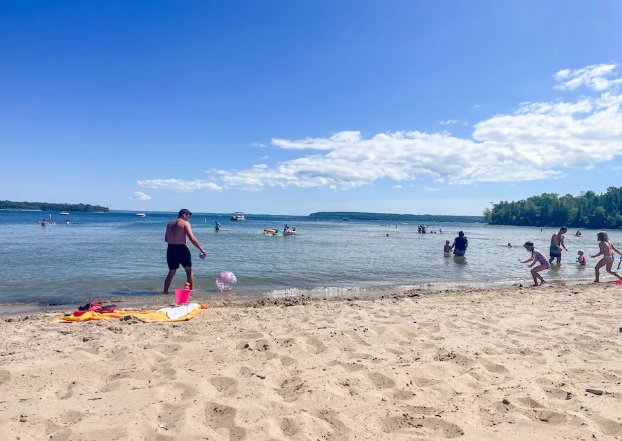 Sandy beach and Lake Michigan with kids and adults playing in the water.