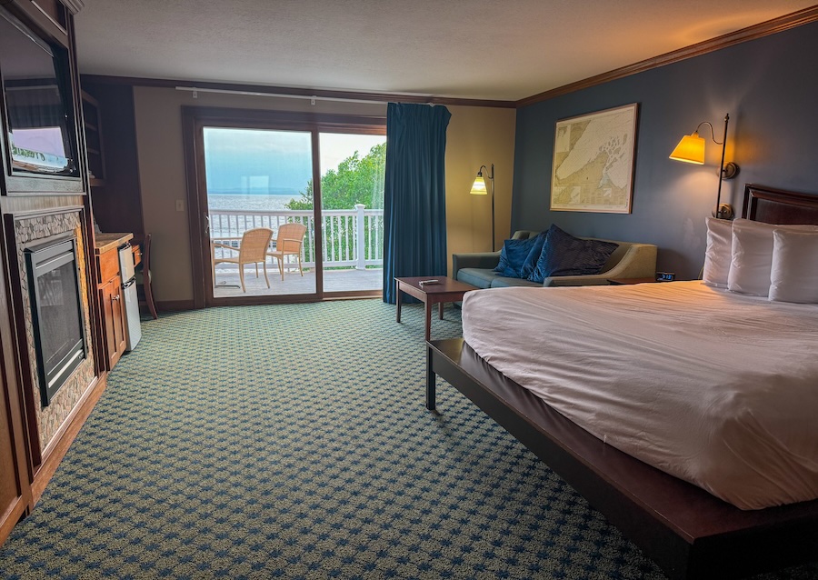 Large room featuring king bed, TV, couch, and sliding glass door with view of Lake Superior - Madeline Island